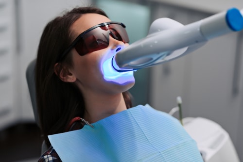 female patient at dentist with ultraviolet light UV lamp.